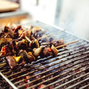 Close-up of delicious skewers grilling over hot charcoal with smoke rising.